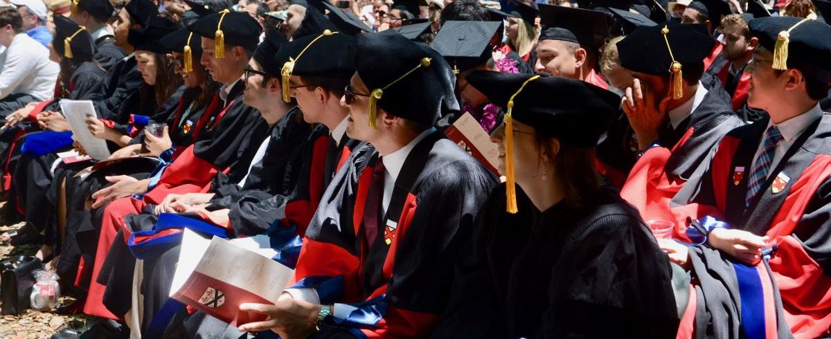 Graduates sitting in regalia, PoliSci Diploma Ceremony