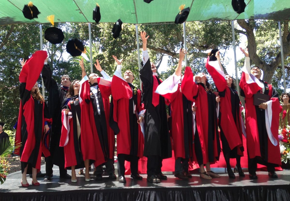 students throwing mortarboards in the air post-graduation